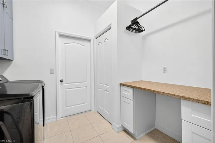 Laundry room with cabinet space, light tile patterned floors, and washing machine and dryer