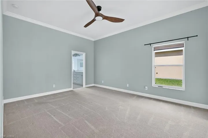 Spare room with crown molding, light colored carpet, and a ceiling fan