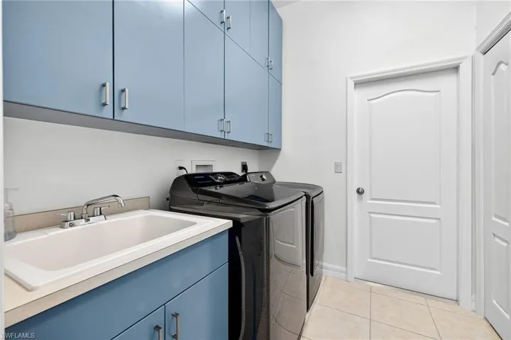 Laundry room featuring cabinet space, light tile patterned floors, and washing machine and dryer