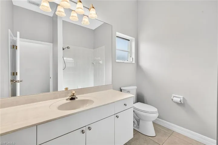 Full bath with light tile patterned floors, vanity, and tiled shower
