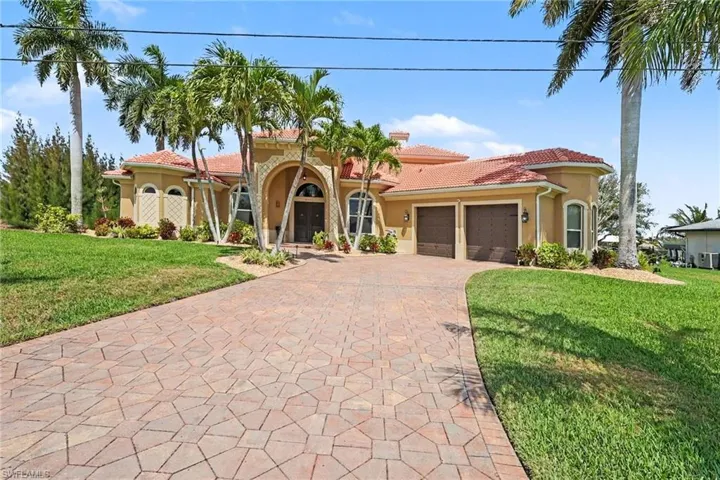 Mediterranean / spanish-style house with a front lawn, stucco siding, a tile roof, decorative driveway, and a garage