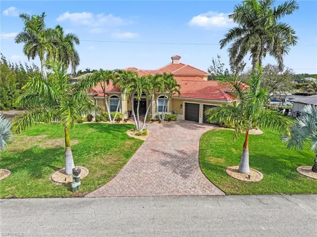 Mediterranean / spanish home featuring a tile roof, decorative driveway, an attached garage, stucco siding, and a front yard