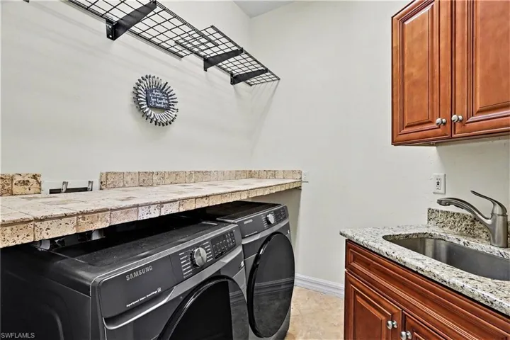 Laundry room featuring washer and clothes dryer, cabinet space, and light tile patterned floors