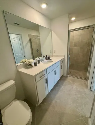 Full bath with vanity, a stall shower, and light tile patterned floors