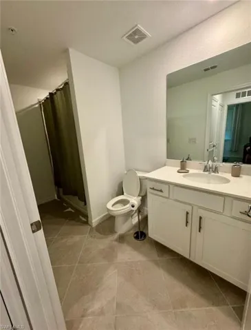 Full bathroom with vanity, a shower stall, light tile patterned flooring, and a textured wall