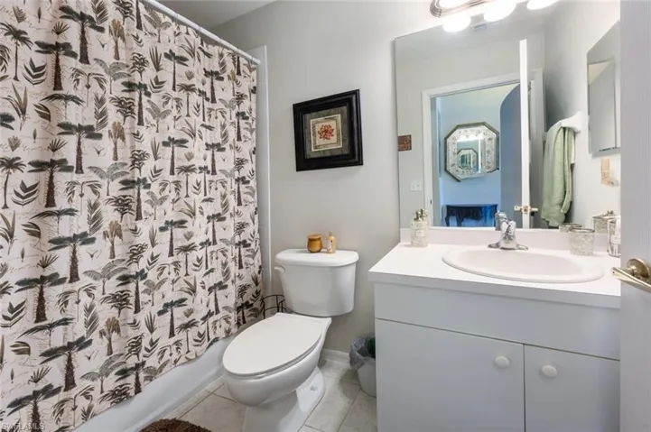 Bathroom with light tile patterned floors, vanity, and shower / bath combo with shower curtain