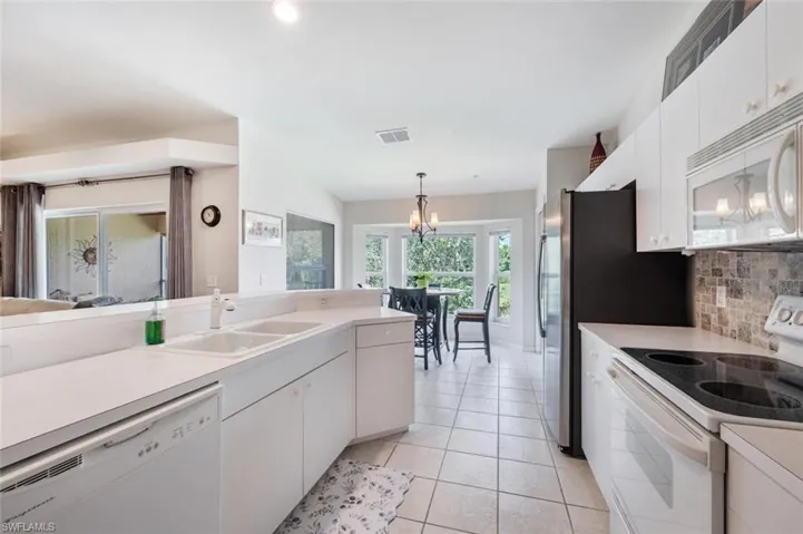 Kitchen with white cabinetry, white appliances, and light countertops
