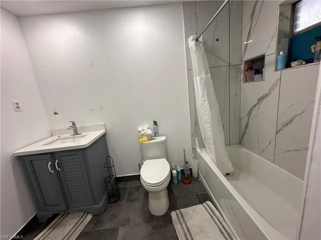 Full bathroom featuring tile patterned floors, vanity, toilet, and shower / tub combo with curtain