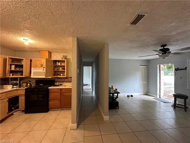 Kitchen featuring light tile patterned floors, a textured ceiling, ceiling fan, and gas stove