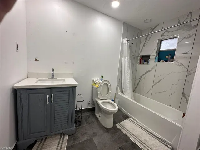 Full bathroom with shower / tub combo with curtain, vanity, tile patterned flooring, and toilet