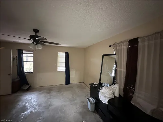 Unfurnished bedroom with concrete flooring, a textured ceiling, and ceiling fan