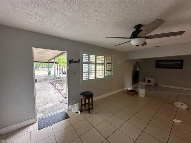 Entrance foyer with a textured ceiling, ceiling fan, and light tile patterned floors