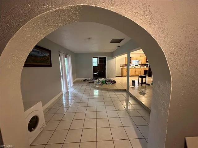 Hall with tile patterned floors and washer / dryer