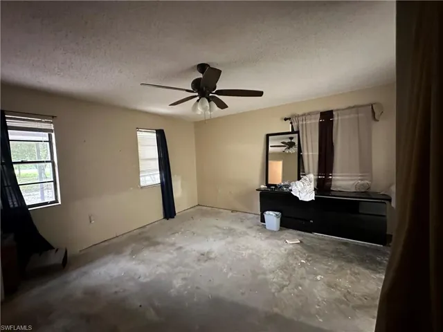 Unfurnished bedroom with a textured ceiling, ceiling fan, and concrete flooring