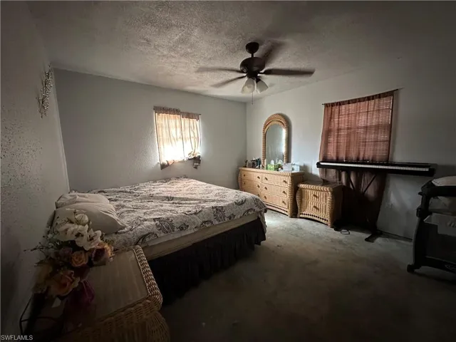 Carpeted bedroom with a textured ceiling and ceiling fan