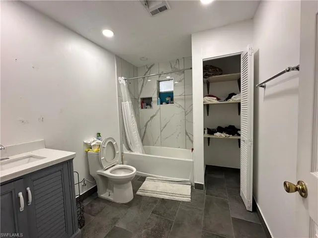 Full bathroom featuring shower / tub combo, tile patterned floors, toilet, and vanity