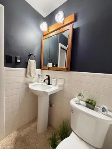 Bathroom featuring a wainscoted wall, tile walls, and speckled floor