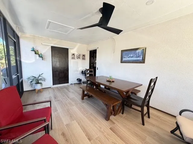 Dining room with attic access, light wood-style flooring, and ceiling fan