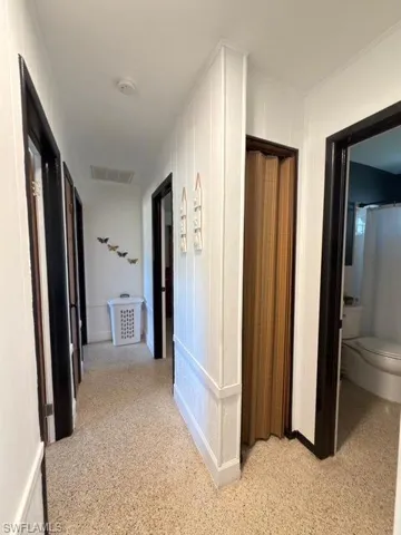 Hallway with dark speckled floor and a decorative wall