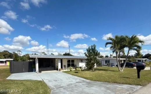 Ranch-style house featuring a front lawn, driveway, and an attached carport