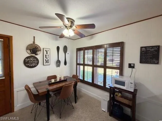 Dining area featuring ceiling fan and light colored carpet