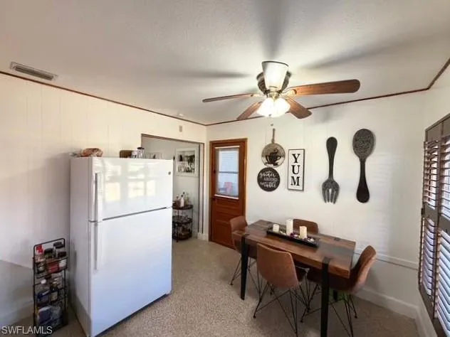 Dining area featuring dark speckled floor and a ceiling fan