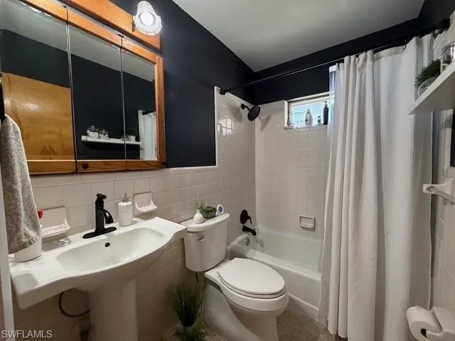 Bathroom featuring tile walls, shower / tub combo with curtain, and tasteful backsplash