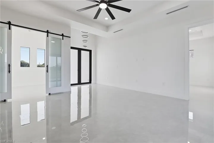 Unfurnished room featuring a barn door, a ceiling fan, a high ceiling, and concrete floors