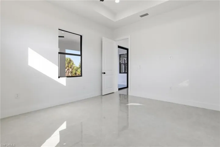 Unfurnished room featuring finished concrete flooring and a raised ceiling