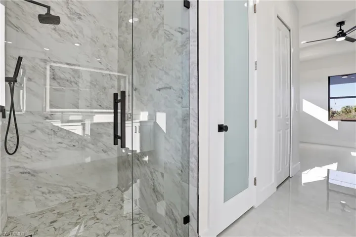 Bathroom featuring a marble finish shower and a ceiling fan