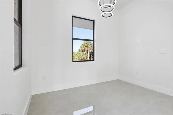 Unfurnished room with a chandelier and concrete floors