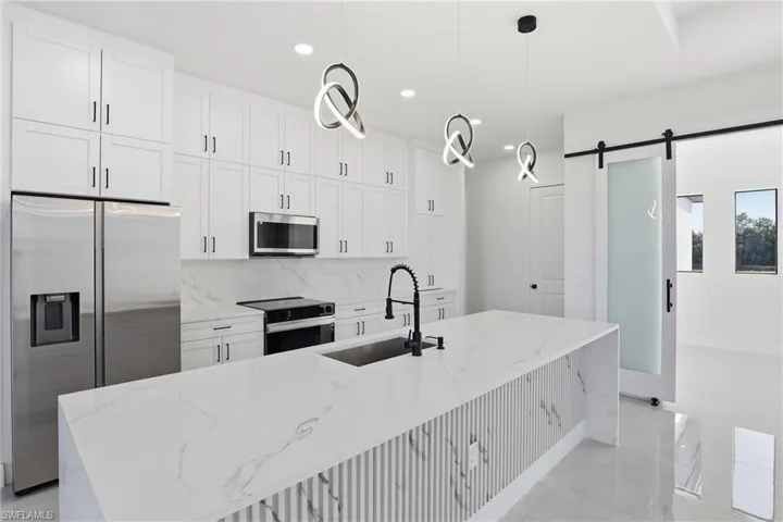Kitchen featuring light stone countertops, decorative backsplash, white cabinetry, appliances with stainless steel finishes, and recessed lighting