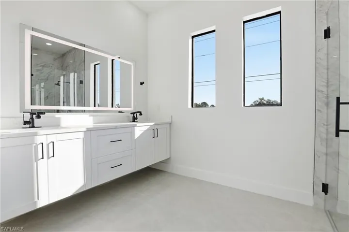 Bathroom featuring a marble finish shower and double vanity