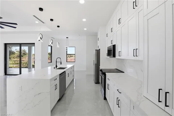 Kitchen featuring white cabinetry, light stone counters, stainless steel appliances, pendant lighting, and recessed lighting