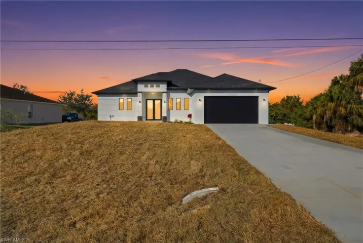 Prairie-style house featuring concrete driveway, an attached garage, stucco siding, and a front lawn