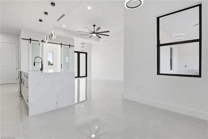 Kitchen featuring ceiling fan, pendant lighting, white cabinets, light stone countertops, and recessed lighting