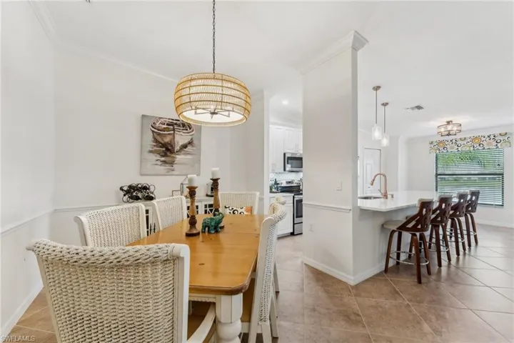 Dining area with light tile patterned flooring, ornamental molding, and sink
