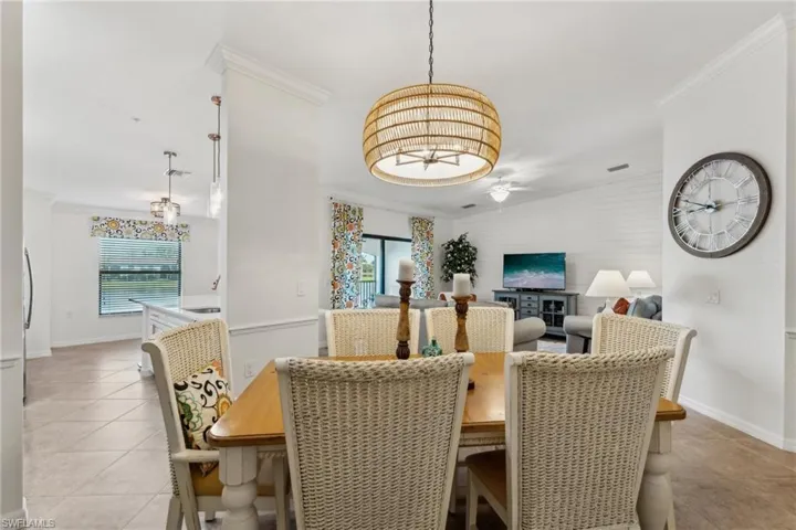 Tiled dining room with crown molding and ceiling fan with notable chandelier