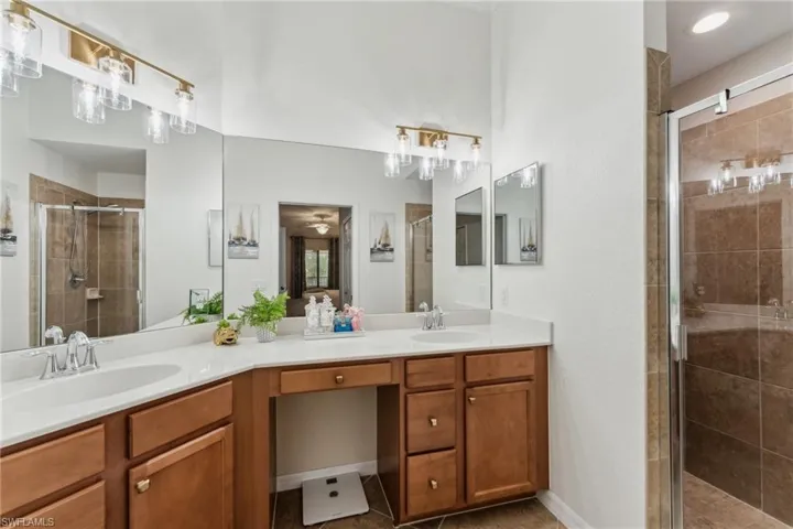 Bathroom featuring ceiling fan, tile patterned floors, vanity, and an enclosed shower