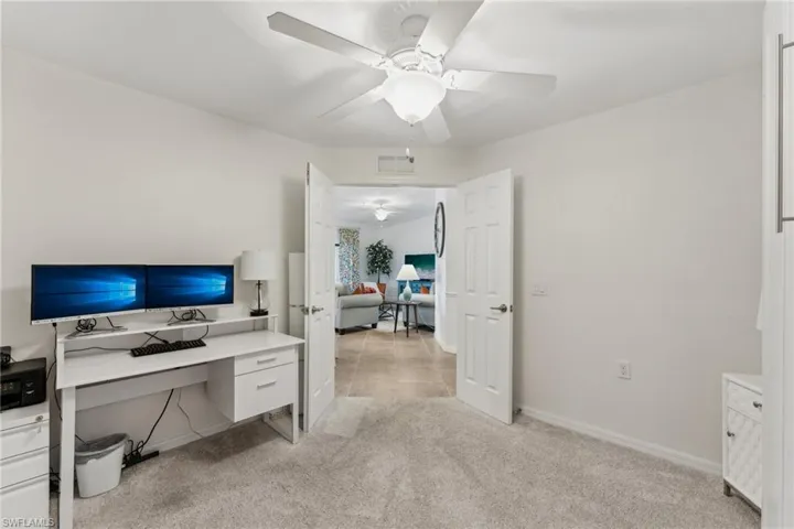 Home office with light colored carpet and ceiling fan