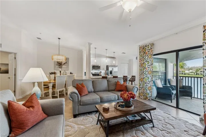 Living room with ornamental molding, light tile patterned floors, and ceiling fan