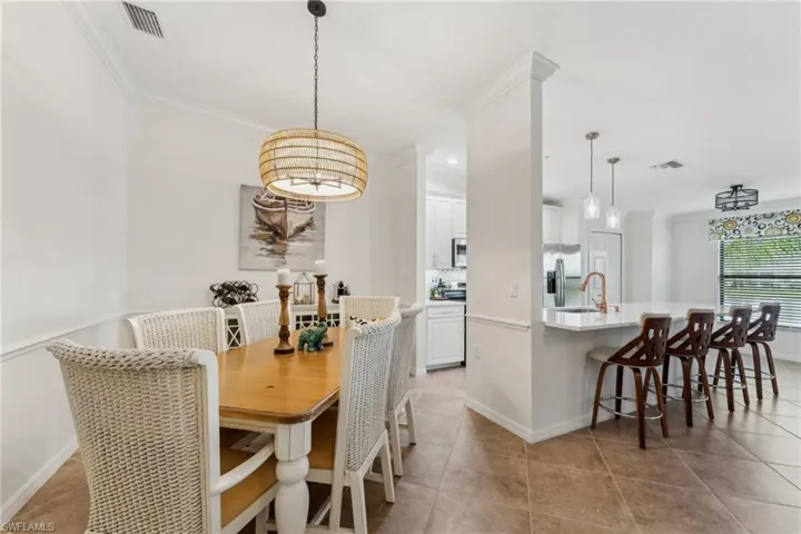 Dining room featuring light tile patterned floors, ornamental molding, and sink