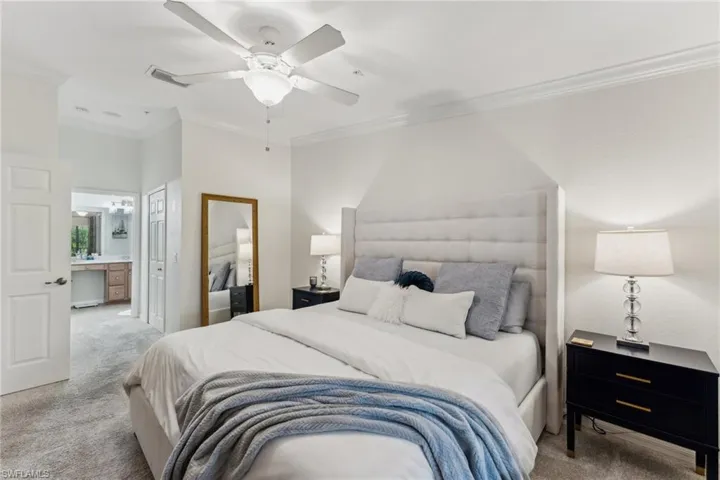 Carpeted bedroom featuring ornamental molding, connected bathroom, ceiling fan, and a closet