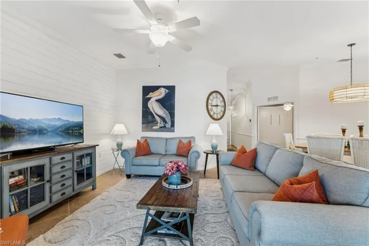 Living room with light tile patterned floors, crown molding, and ceiling fan