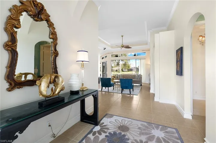 Corridor featuring crown molding, a tray ceiling, and light tile patterned floors