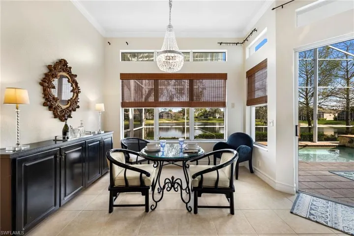 Dining room featuring crown molding, a notable chandelier, light tile patterned floors, a water view
