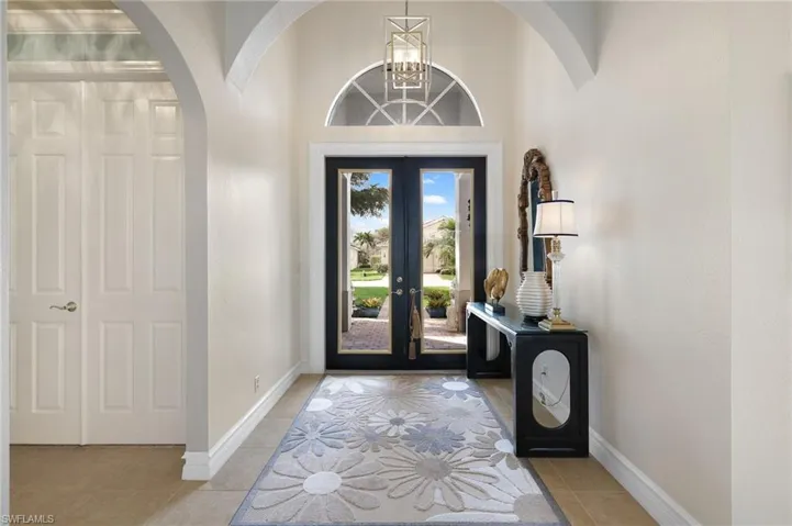 Foyer entrance, a chandelier, french doors, and light tile patterned flooring
