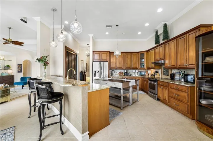 Kitchen with pendant lighting, under cabinet ighting, appliances with stainless steel finishes, a kitchen breakfast bar