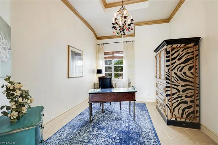Office with light tile patterned floors, an inviting chandelier, a tray ceiling, and crown molding