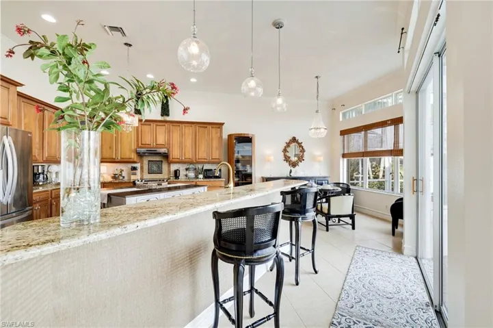 Kitchen featuring hanging pendants, a breakfast bar area, and light stone countertops